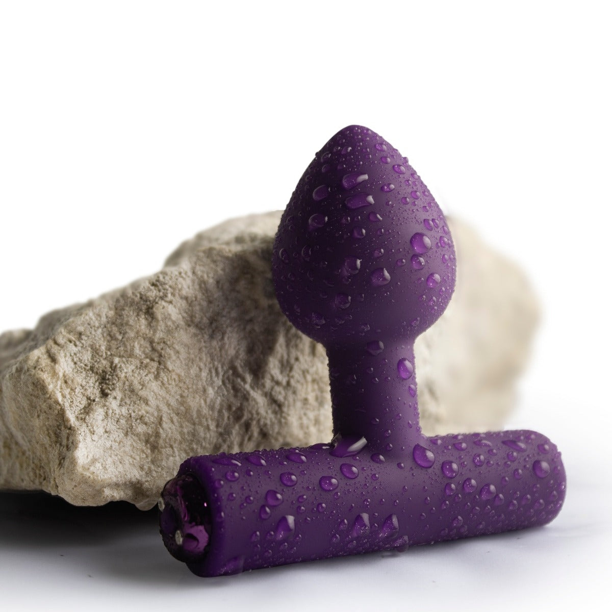 Rocks Off Astryx Rechargeable Plug Purple against a rock showing its waterproof capabilities