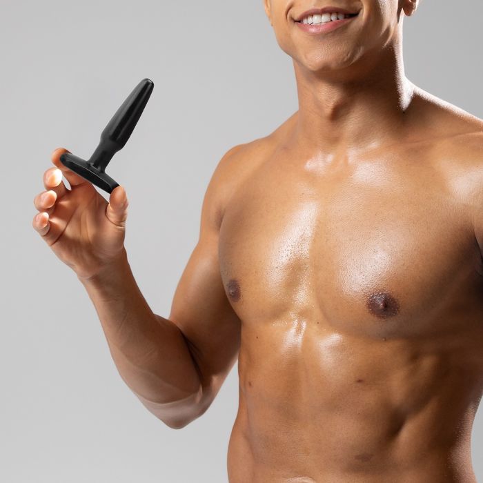 Topless model holding a Me You Us butt plug black